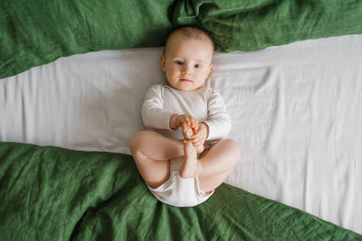 Portrait of a cute charming smiling laughing caucasian white boy of six months old lying on a bed