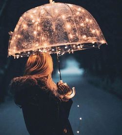 Rear view of woman holding umbrella