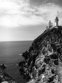 Lighthouse by sea against sky