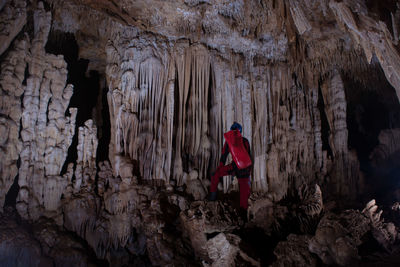 Rear view of man standing on rock in cave