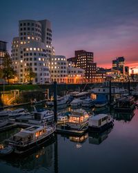 Boats moored at harbor against sky during sunset