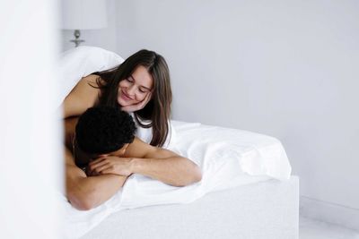 Young couple lying on bed at home smiling at each other