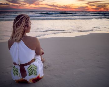 Rear view of woman sitting on beach