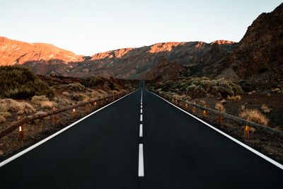 Empty road along landscape and mountains against sky