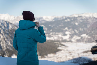 Rear view of man looking at snowcapped mountain