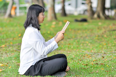 Side view of woman using mobile phone in field