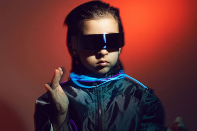 Portrait cyberpunk boy child in vr glasses in blue and red tones with wires. game, virtual reality