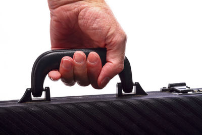 Close-up of hand holding book against white background