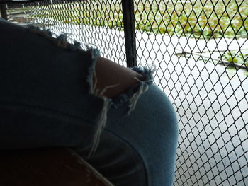 Low section of person by chainlink fence