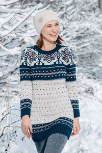 Middle age woman in woollen dress with ethnic pattern walking in park outdoor on sunny winter day