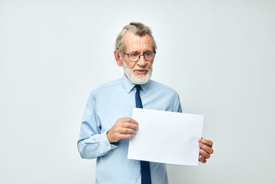 Senior man holding paper against white background