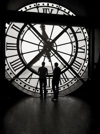 Silhouette people standing against clock tower