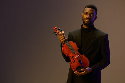 Young man playing violin against white background