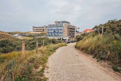 Footpath amidst buildings against sky