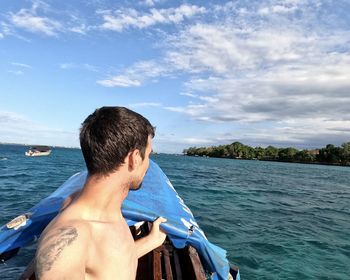 Rear view of shirtless man in sea against sky