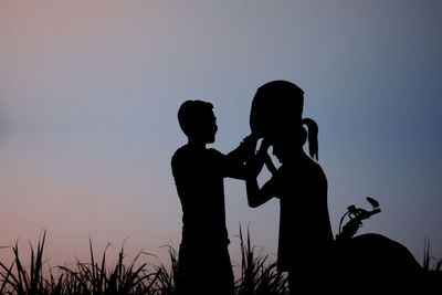 Silhouette couple standing against sky during sunset