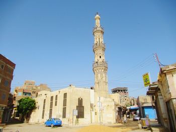 View of street and buildings against clear blue sky