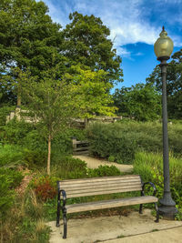 Street light by trees in park against sky