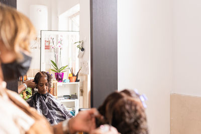 Cropped hands of hairdresser styling customers hair at salon