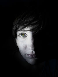 Close-up portrait of young woman against black background