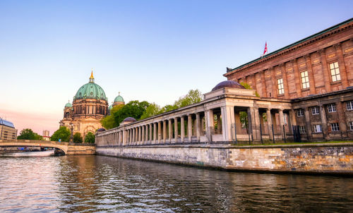 View of building by river against sky in city