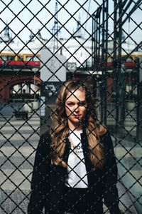 Portrait of young woman looking through fence