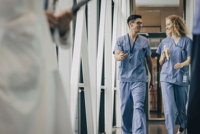 Smiling male and female healthcare staff walking in corridor of hospital