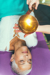 Cropped hands of woman playing singing bowl for customer in spa