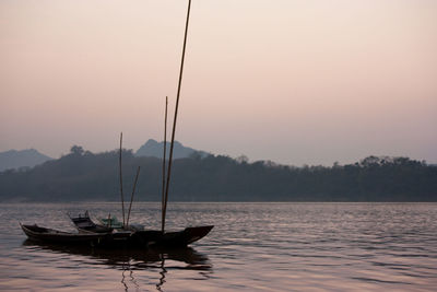 Sailboats in lake against sky during sunset