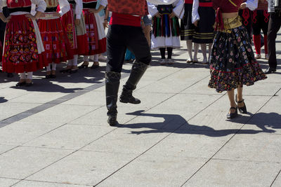 Low section of people in traditional clothing walking on footpath