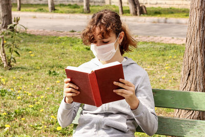 Full length of woman reading book on field