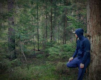 Man standing on tree trunk in forest