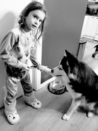 Cute girl playing with dog at home