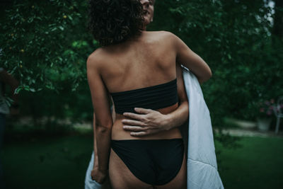 Rear view of woman standing against trees