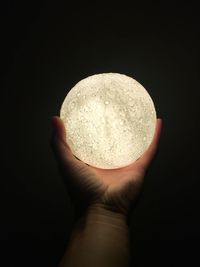 Close-up of hand holding ice cream against black background