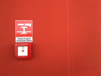 Danger sign and push button on red wall