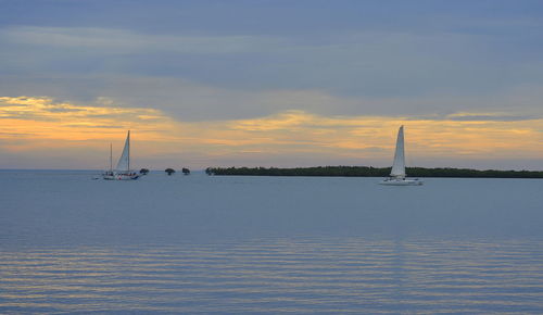 Sailboat sailing on sea against sky during sunset