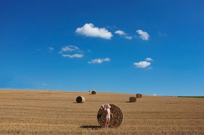 Hay bales on field against blue sky