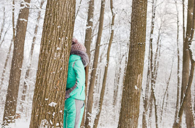 Rear view of man on tree trunk during winter
