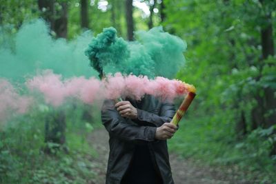 Man holding distress flare while standing in forest