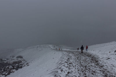 People on snowcapped mountain against sky