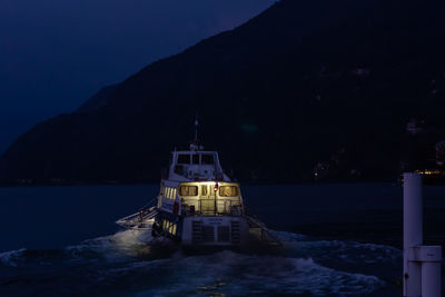 Illuminated building by sea against sky at night