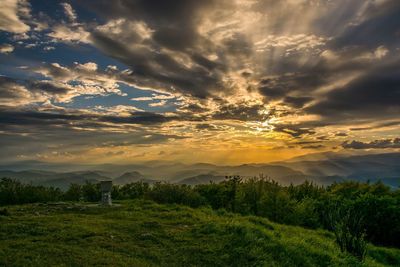 Scenic view of green landscape against sky during sunset