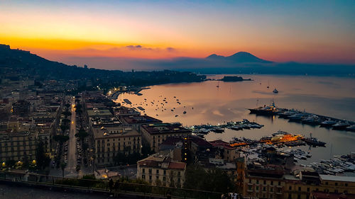 High angle view of buildings by sea against sky during sunset