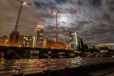 Illuminated buildings in city against cloudy sky