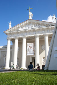 People walking in front of building against sky