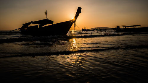 Silhouette of sailboat in sea against sky during sunset