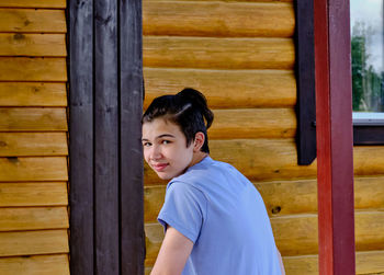 Portrait of a smiling teenager in a blue t-shirt, hair with a ponytail, looking back at the camera 