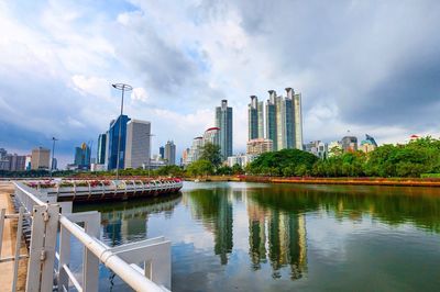 City at waterfront against cloudy sky