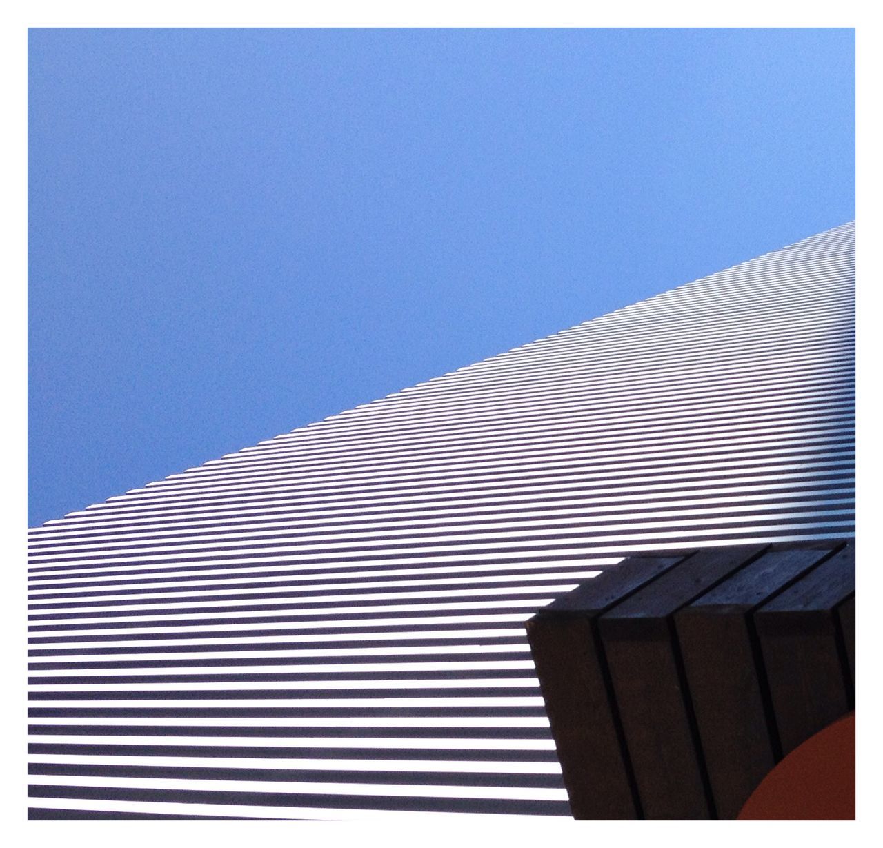 clear sky, low angle view, copy space, blue, transfer print, built structure, architecture, pattern, auto post production filter, building exterior, striped, no people, outdoors, design, day, modern, part of, sunlight, high section, repetition